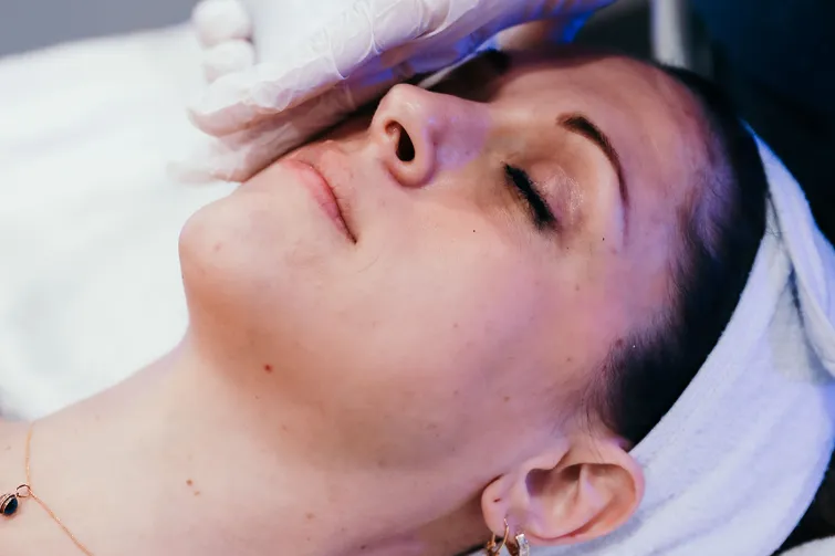 Woman with eyes closed receiving hydrafacial treatment at Restore