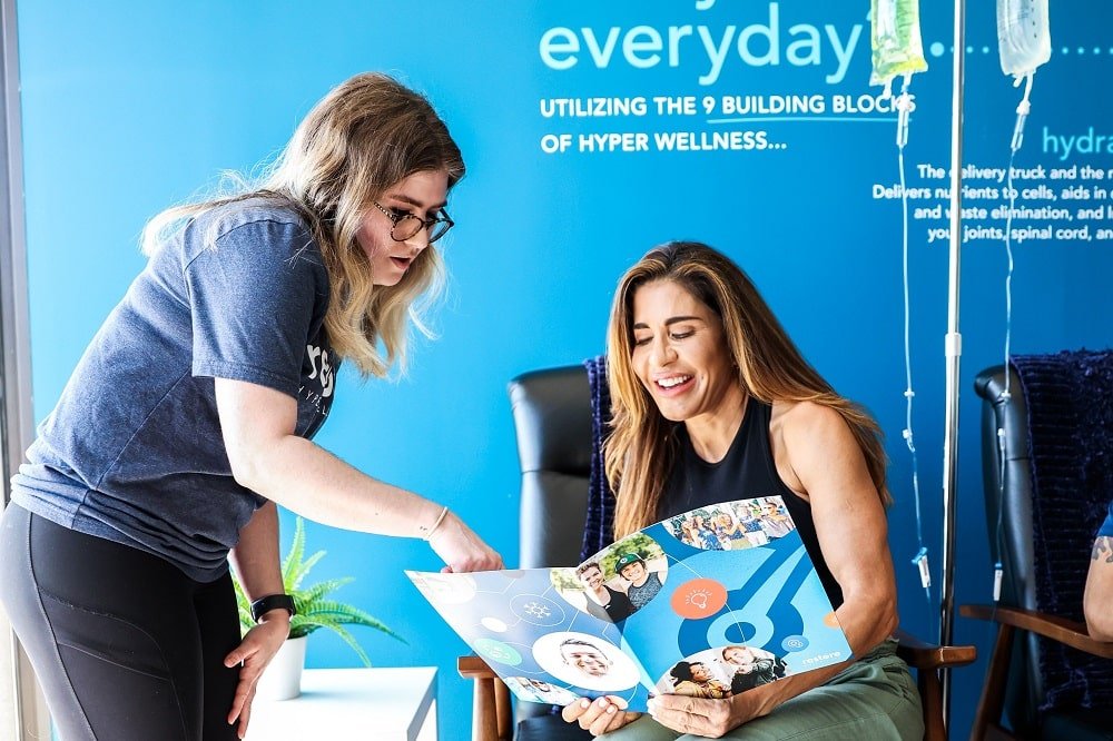 Woman and worker having a conversation and smiling while looking at the catalog of Restore