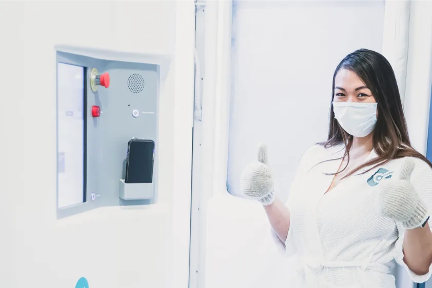 Woman with surgical mask and gloves giving two thumbs up.